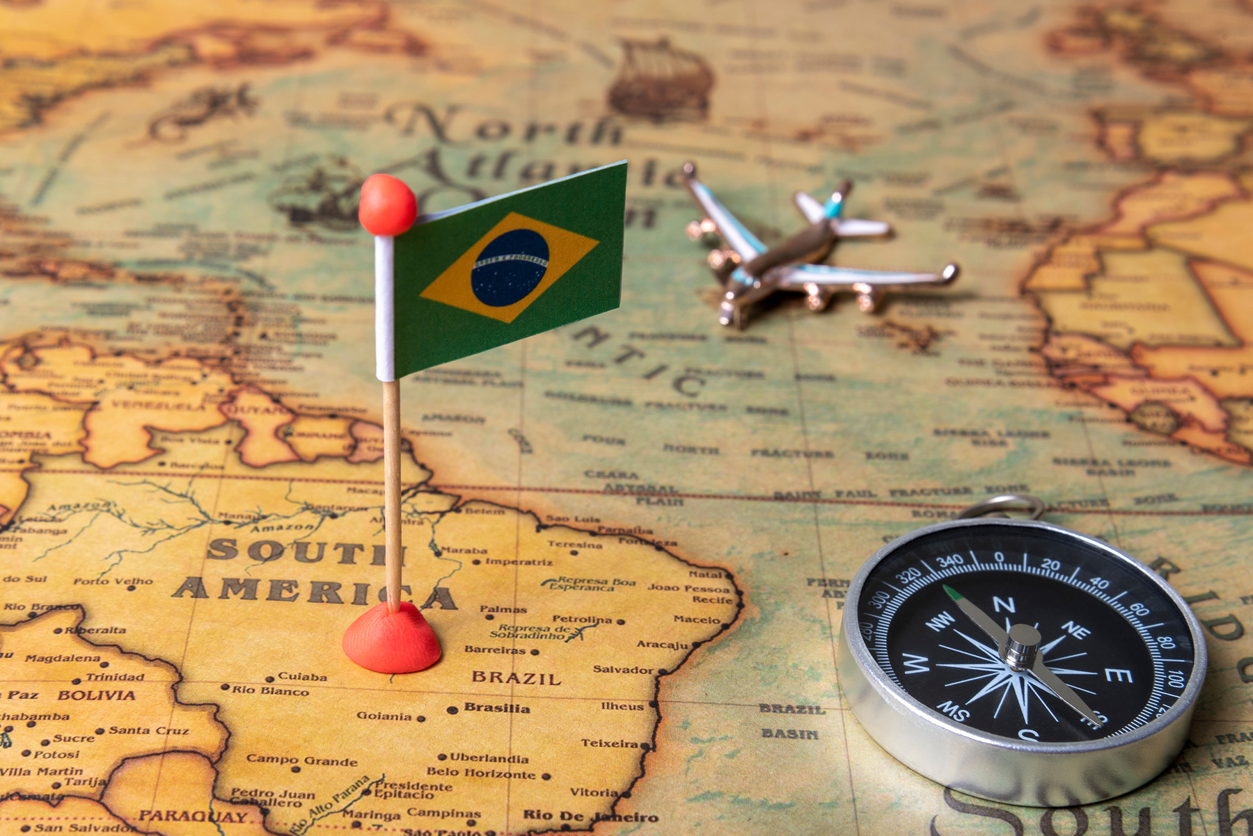 Flag of Brazil, compass and plane on the world map.